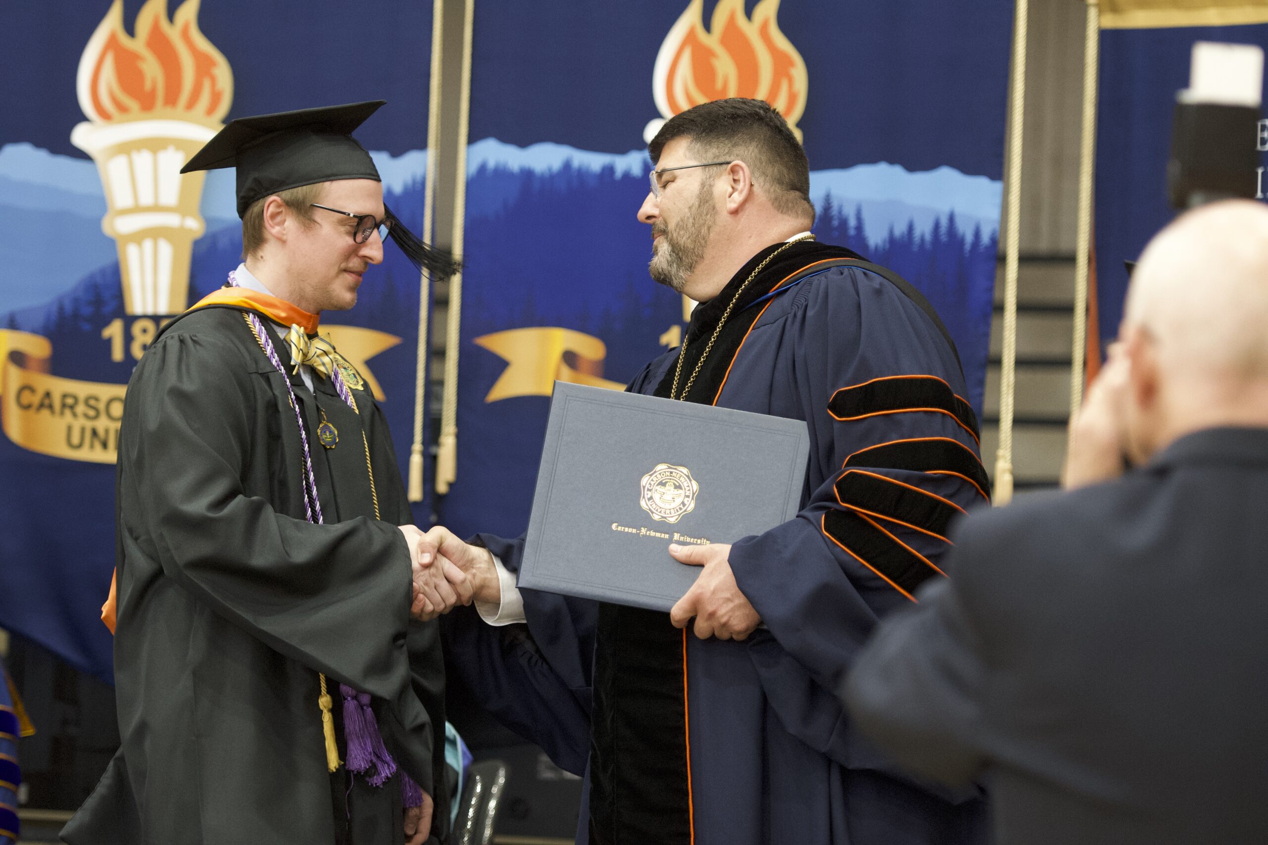 two men wearing black academic robes during a graduation ceremony
